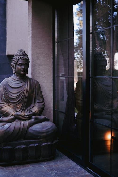A buddha statue sits in front of a glass door