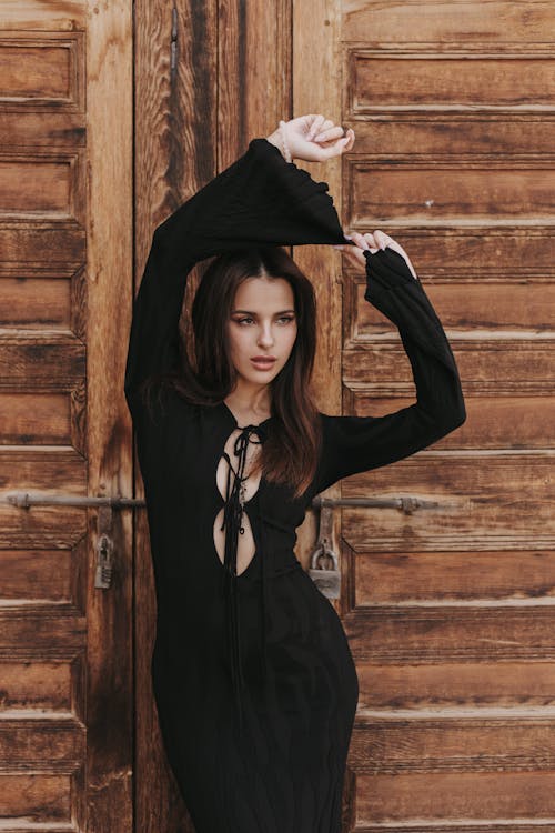 Model Wearing a Black Dress, Posing against Wooden Door