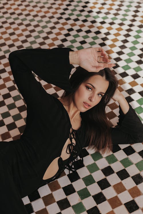 Model Wearing a Black Dress, Lying on a Tiled Checked Floor