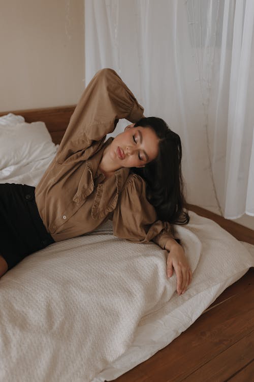 Woman in Brown Blouse in Lying on Bed with Eyes Closed