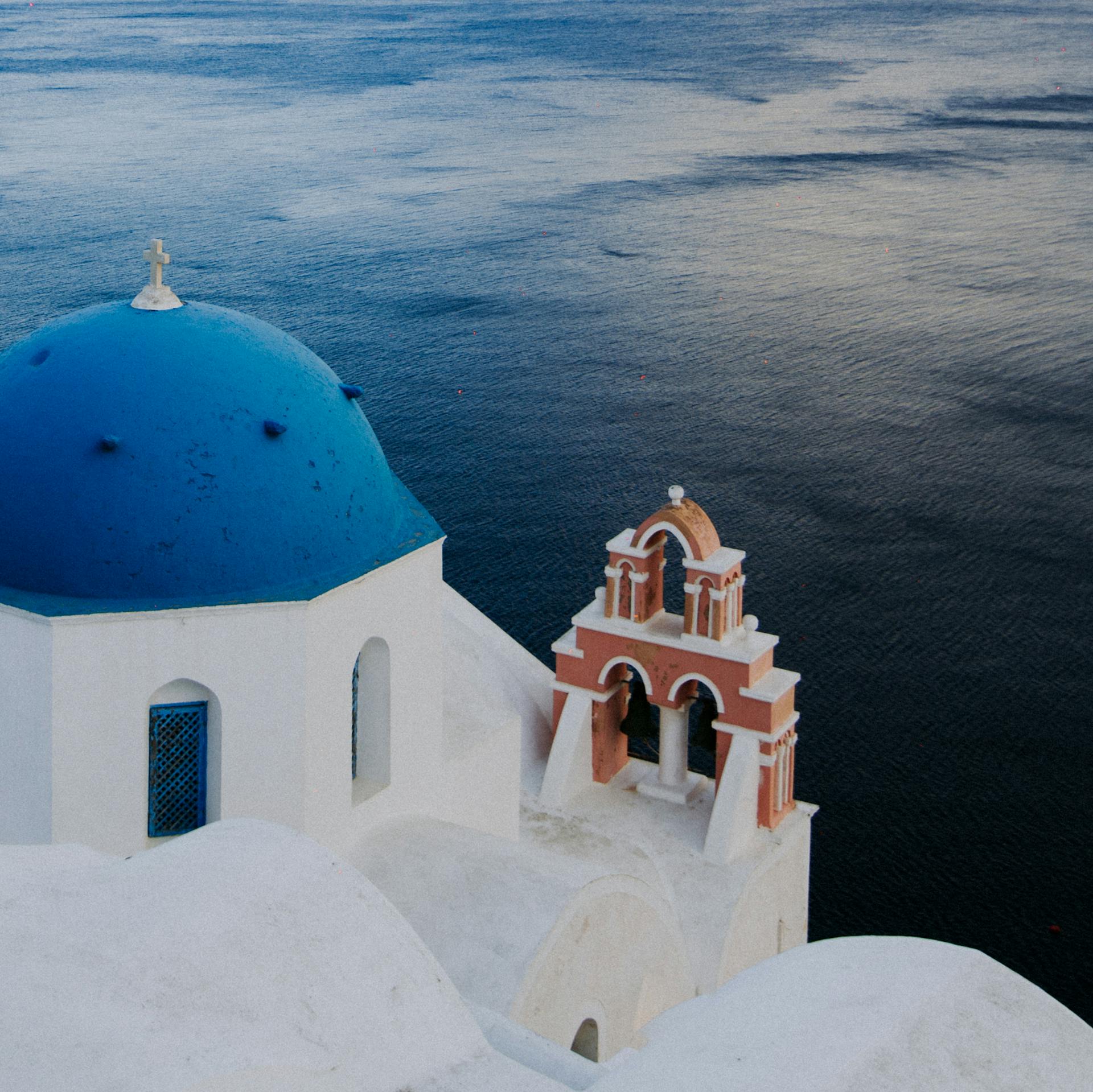 Serene view of the iconic blue dome church in Fira, overlooking the Aegean Sea.