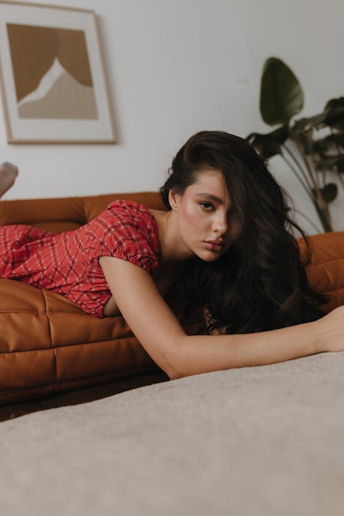 A woman laying on a brown couch with her legs crossed