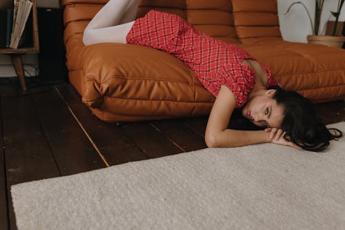 A woman laying on the floor next to a couch