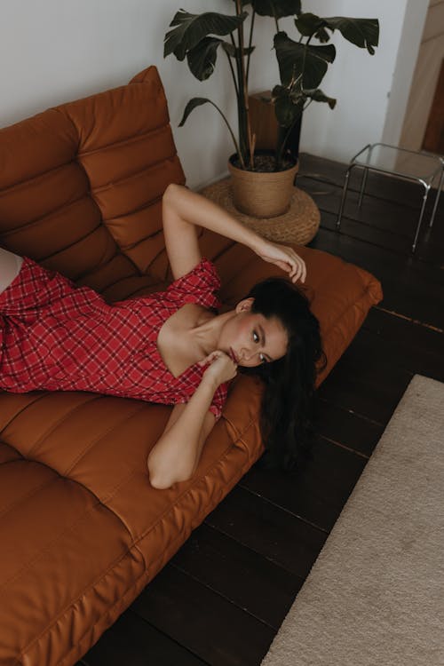 A woman laying on a couch in a red dress