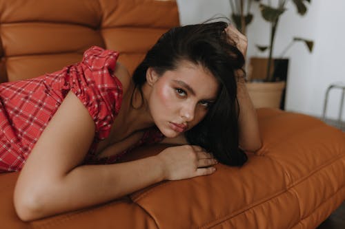 A woman laying on a couch in a red plaid shirt