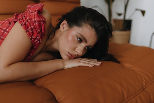 A woman laying on a brown leather couch