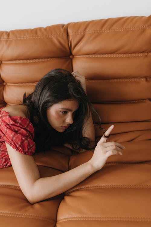 A woman laying on a couch with her hand on her phone