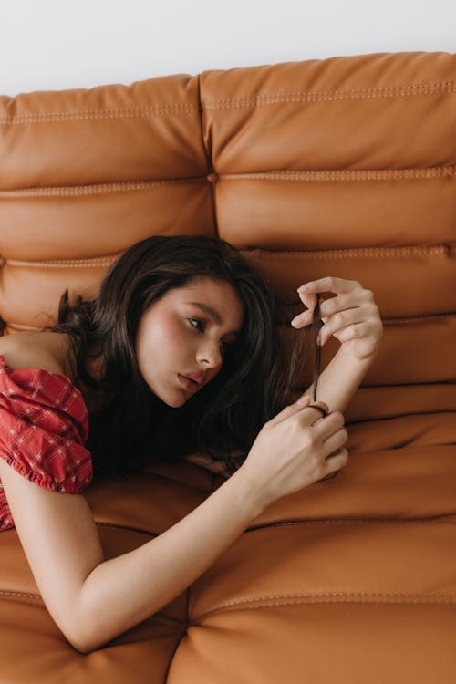 A woman laying on a couch with her hair in her hand