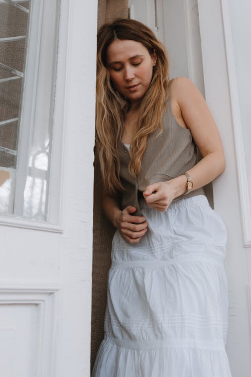 Young Woman in a Vest and White Skirt Standing in the Doorway 