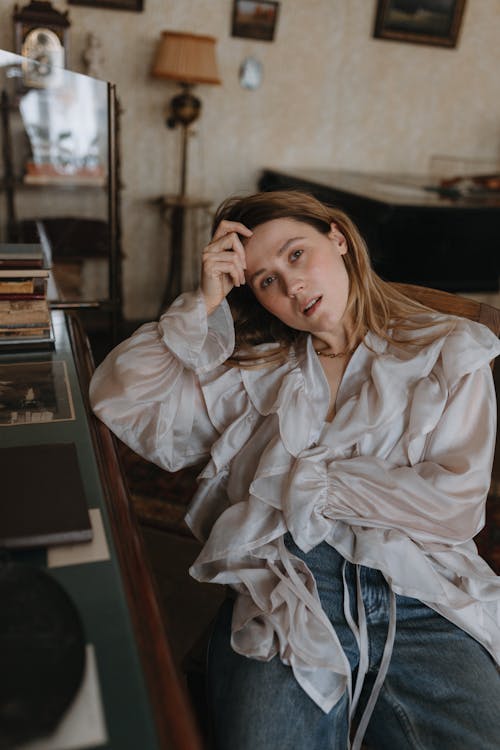 A woman sitting in a chair in front of a bookcase