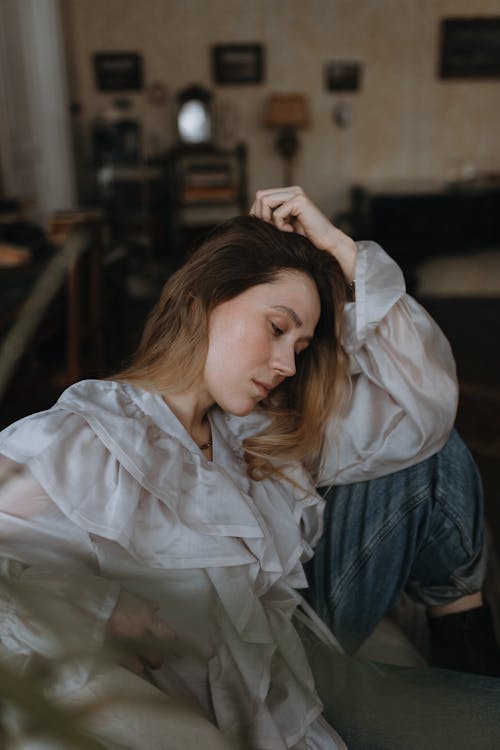 A woman sitting on a couch with her hand on her head