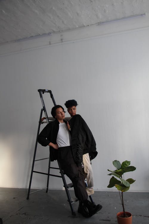 Two people standing on a ladder in a room