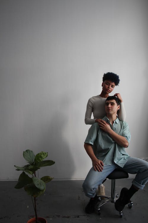Two people sitting on a chair in front of a plant