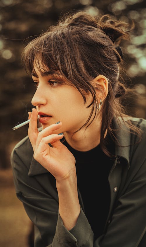 A woman smoking a cigarette in the woods