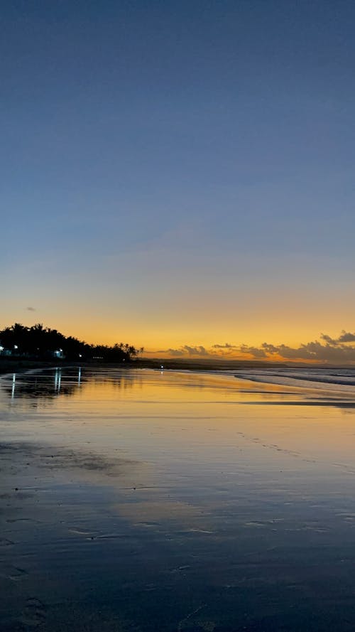 A sunset on the beach with a reflection in the water