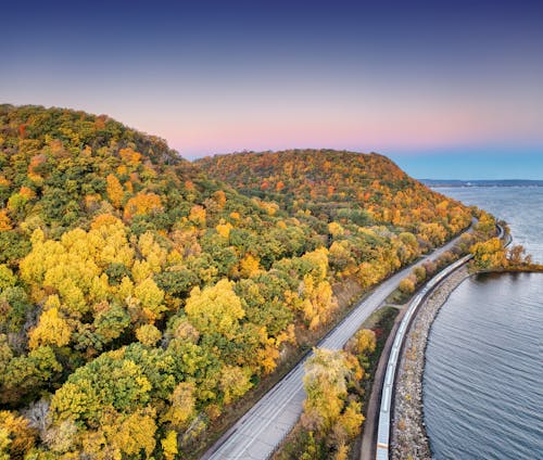 An aerial view of a road and river with fall foliage