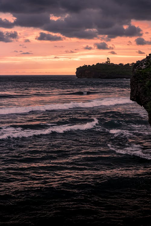 View of Silhouetted Cliffs on a Shore at Sunset
