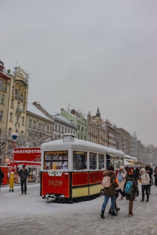 Free A vintage tram on a snowy street with people and historic buildings in a winter city scene. Stock Photo