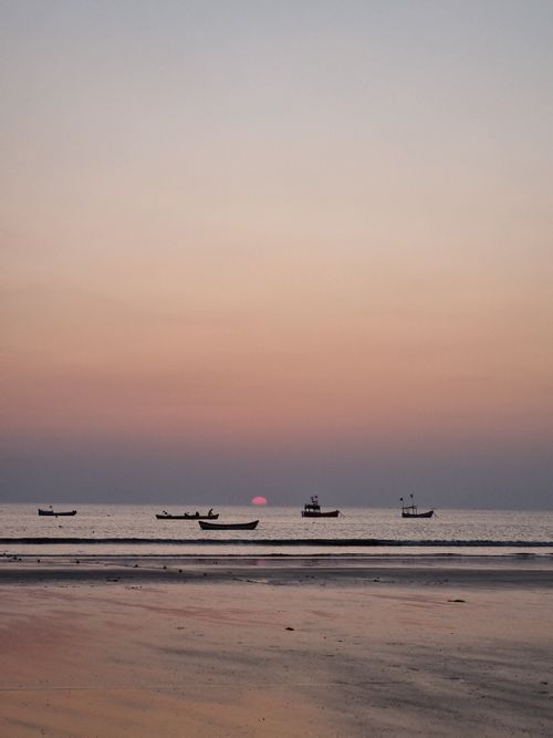 Free Tranquil sunset over Vasai-Virar beach with boats silhouetted against a pink sky. Stock Photo