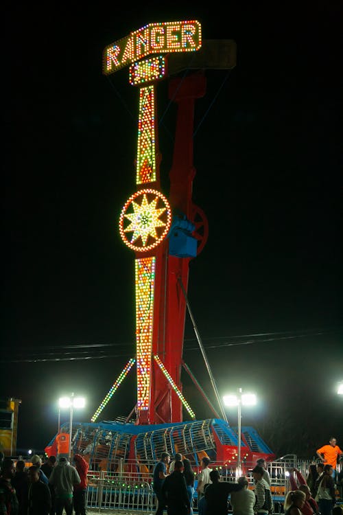 A carnival ride with a large clock and people standing around it