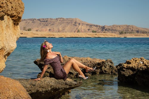A woman sitting on rocks in the water