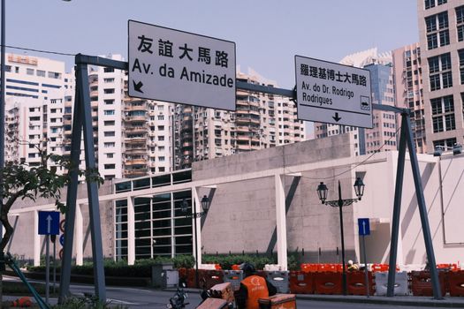 Street view in Macau with bilingual road signs and urban architecture.