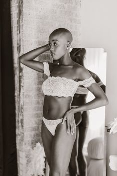 Stunning black and white portrait of a bald woman in stylish white lingerie showing confidence.