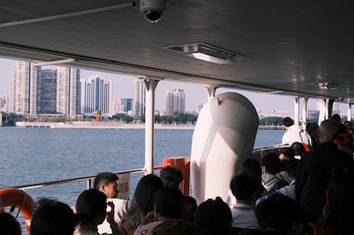 Passengers on Deck of Boat Looking at City