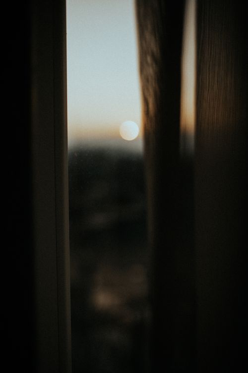 Free A blurred sunset seen through a window frame, evoking a serene evening mood. Stock Photo