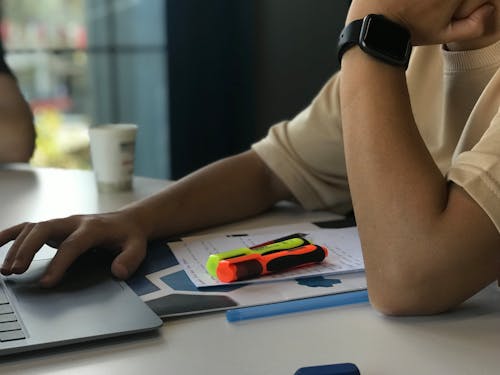 A person sitting at a desk with a laptop and a pen