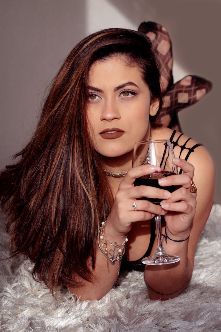 Woman Lying In Bed With Glass Of Wine