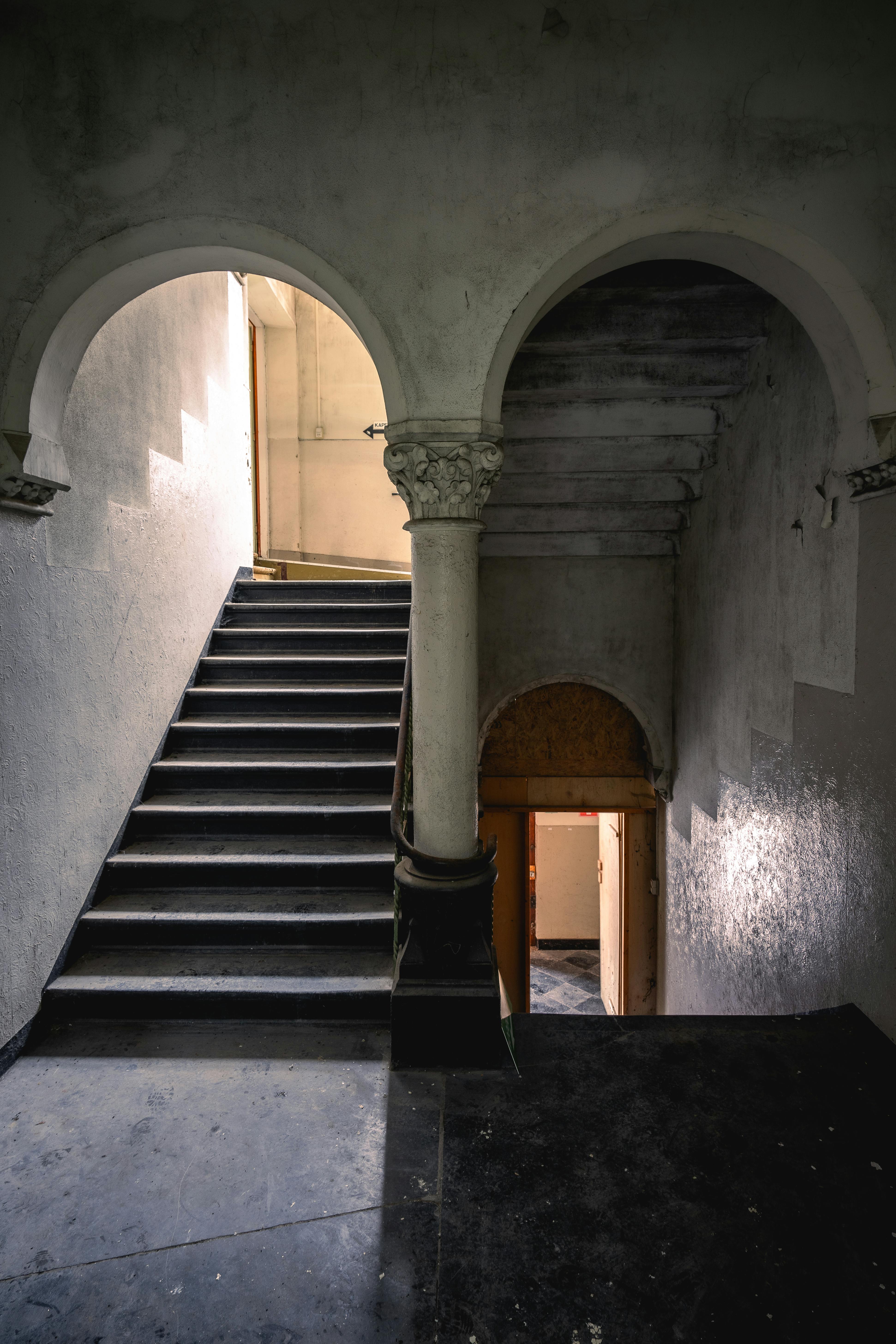 Moody image of an abandoned staircase featuring classic arches and grunge textures.