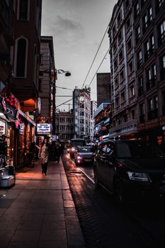 Nighttime city street with illuminated signs, cars, and pedestrians. A blend of urban life and vibrant lights.