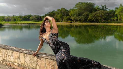 Woman Posing in Black Dress on Wall over Lake
