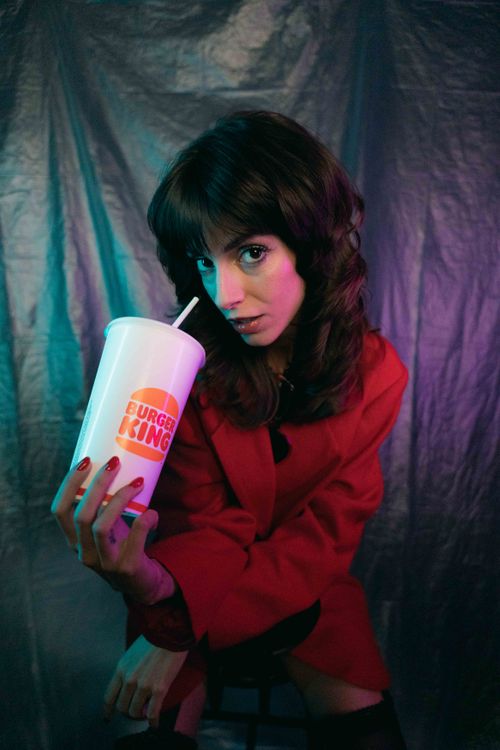 Free Portrait of a woman in a red jacket holding a fast-food beverage cup Stock Photo