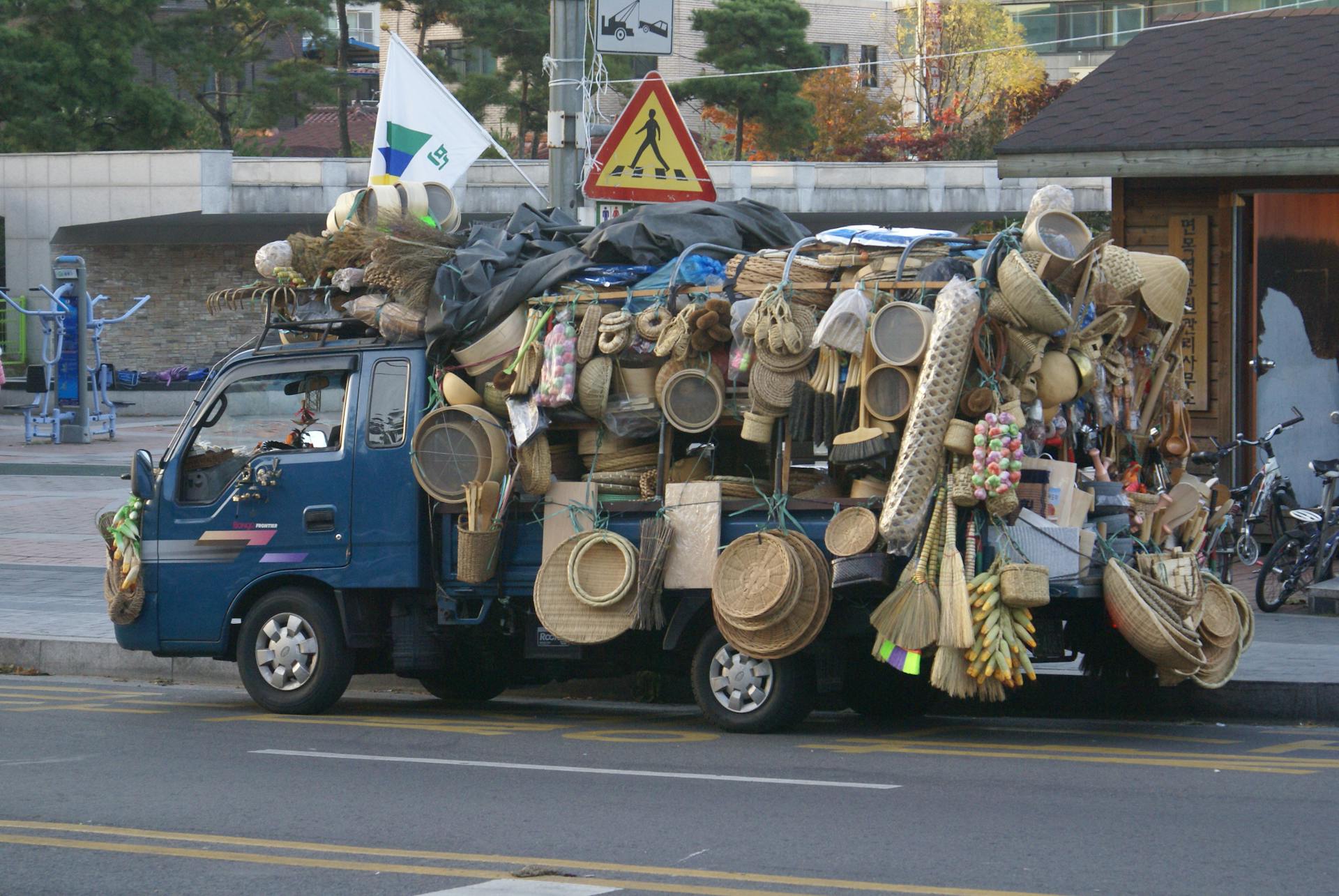 Colorful truck loaded with woven baskets and goods on a city street.