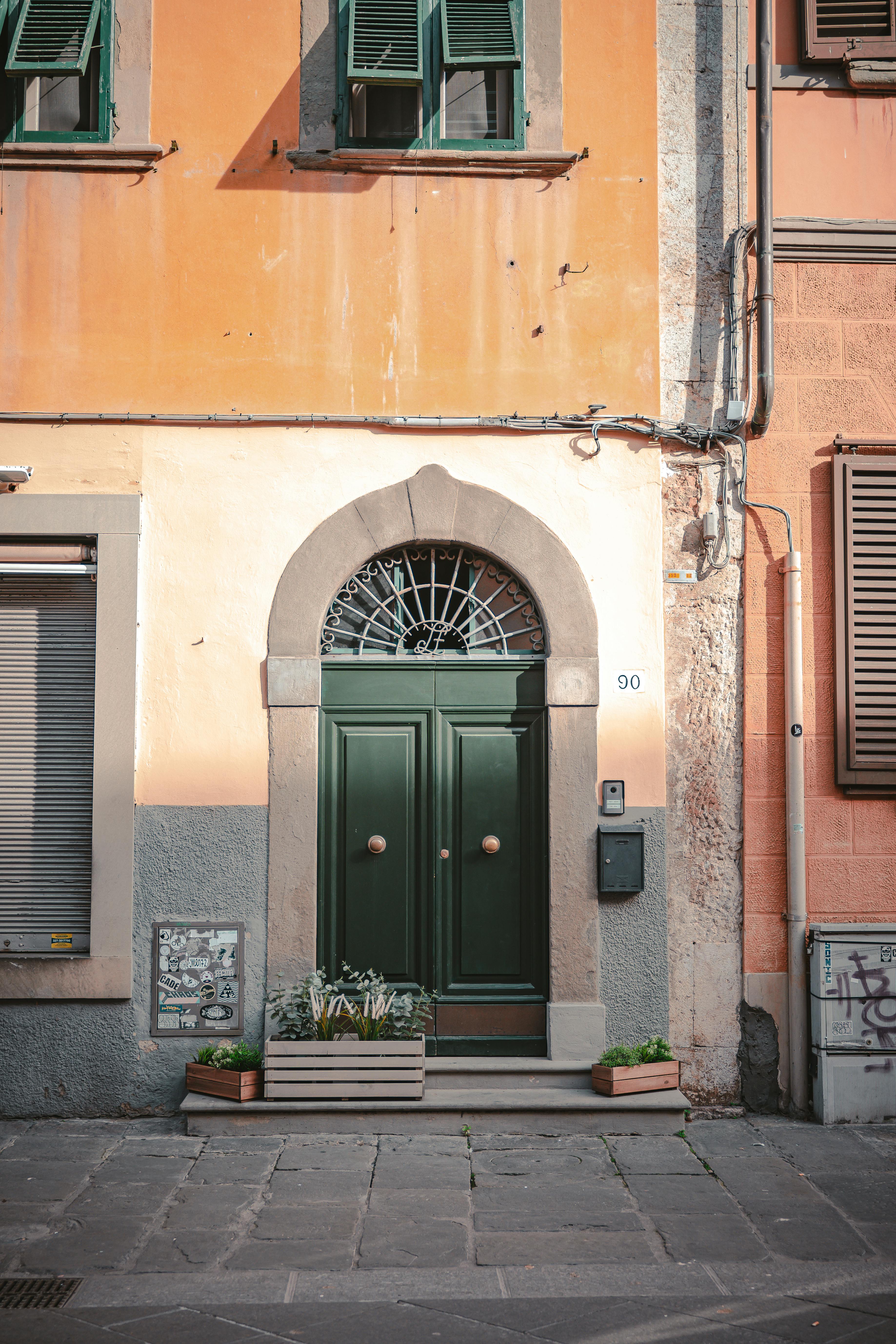Elegant green door on a peach and grey stone facade in urban Europe.