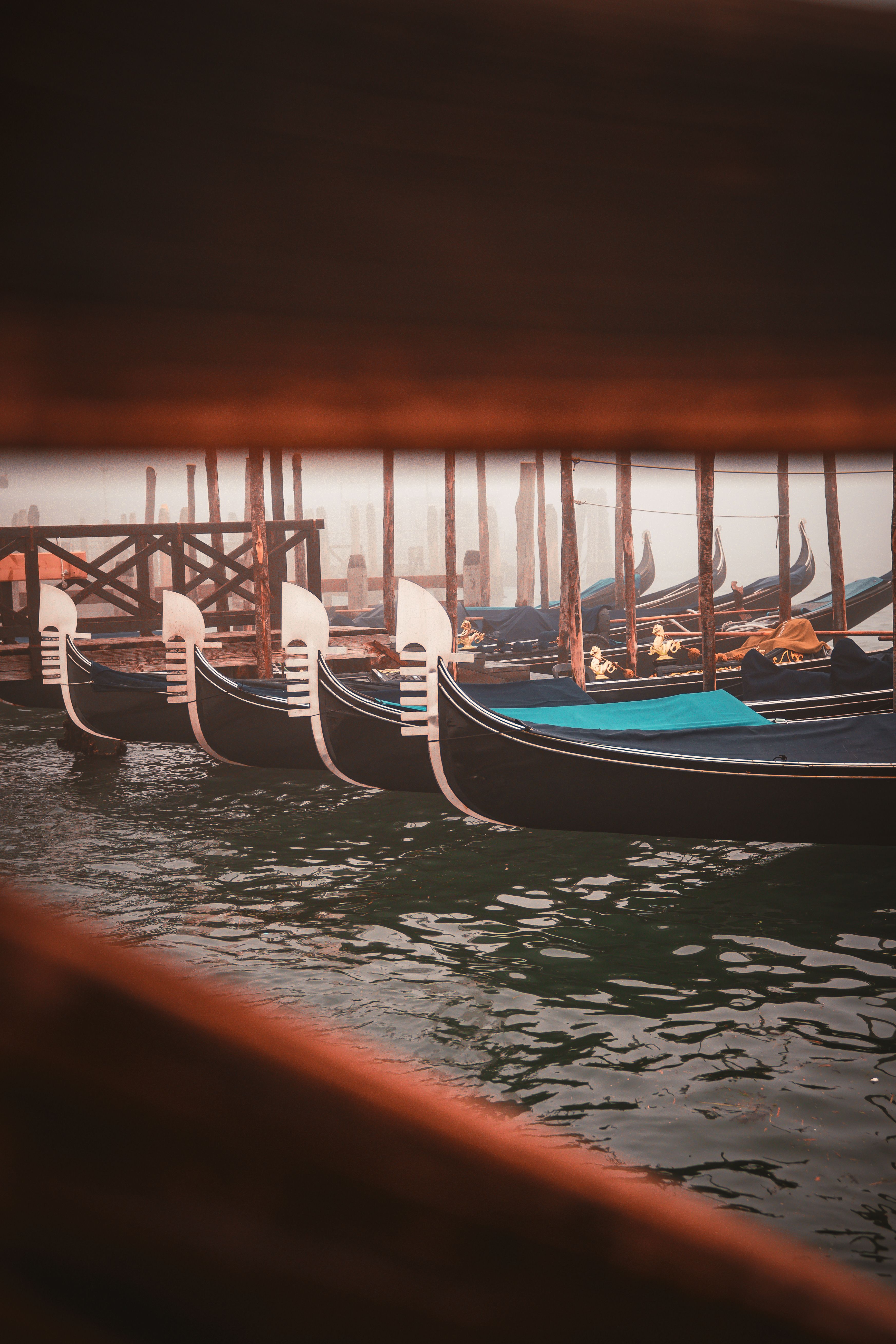 Serene row of moored gondolas in Venice, Italy, enveloped in a calming mist.
