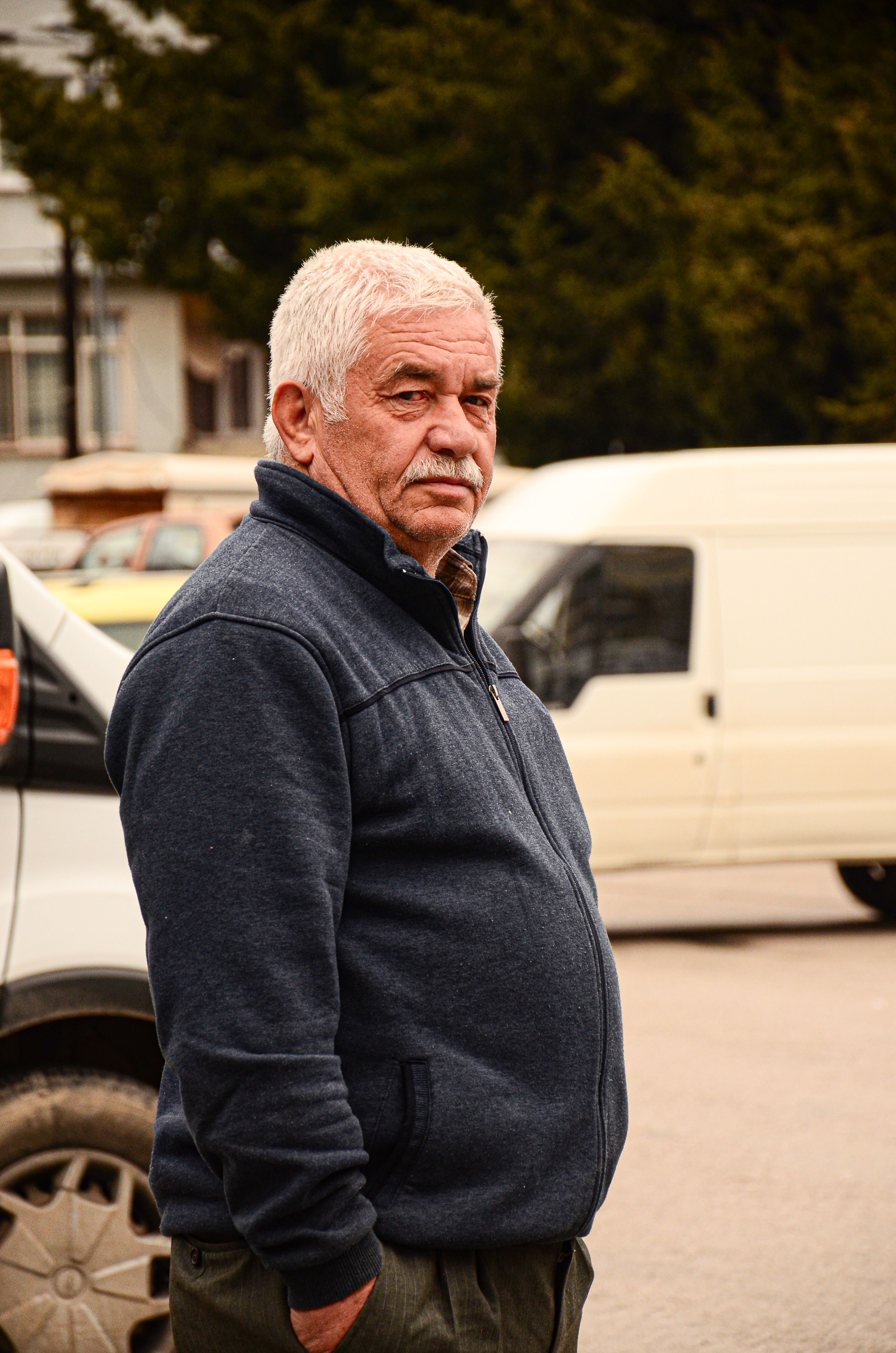 Portrait of a senior man with gray hair standing on a busy city street
