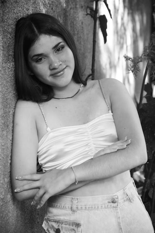 A young woman leaning against a wall in black and white