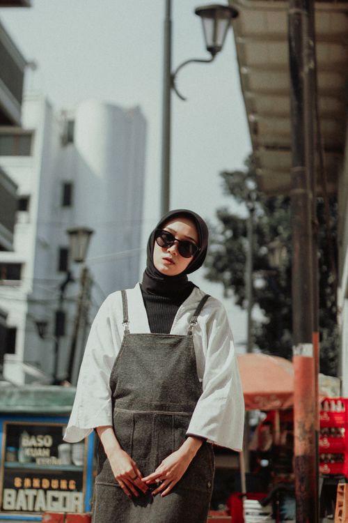 Free Sophisticated woman in hijab and sunglasses poses in trendy urban environment. Stock Photo