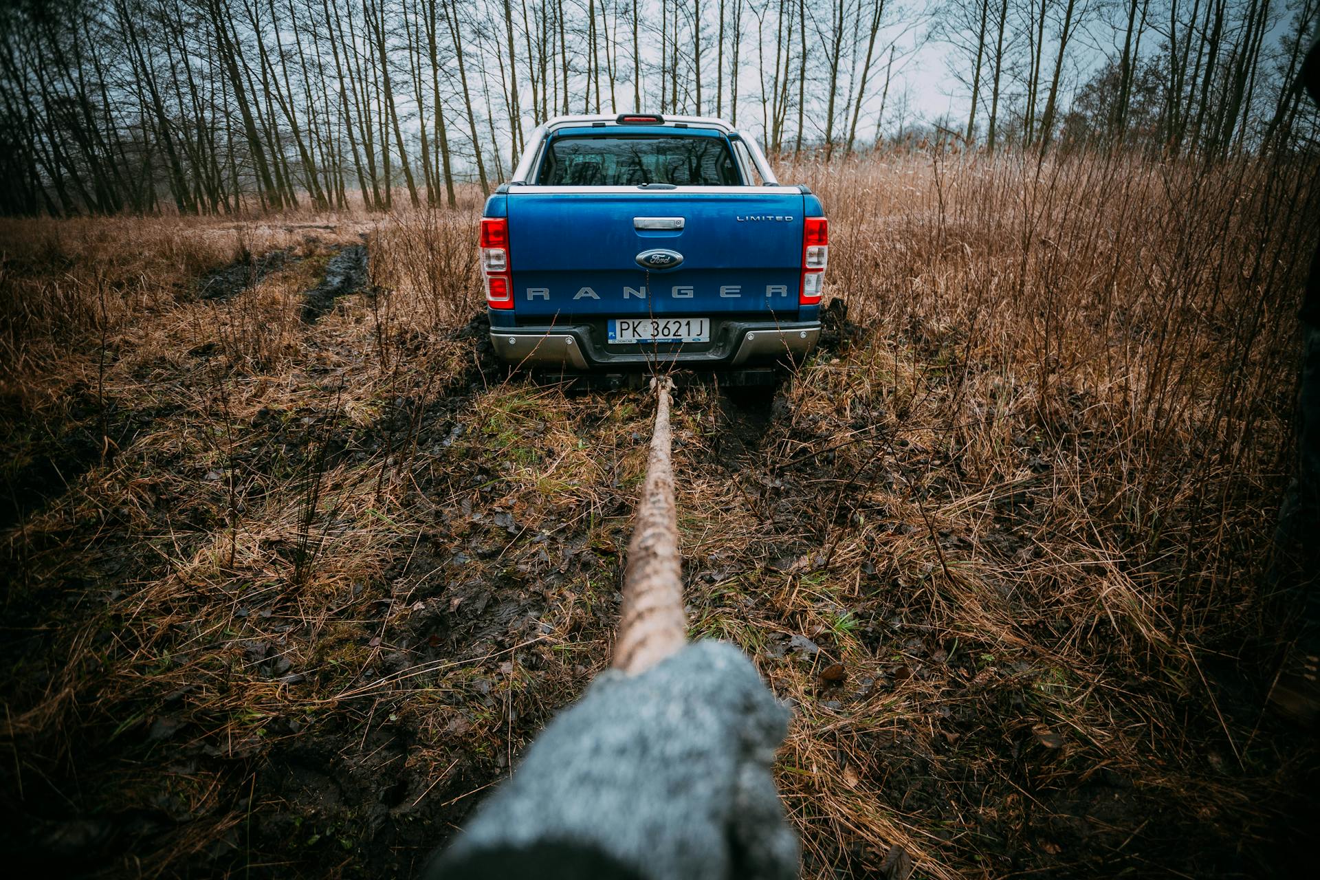 A blue Ford Ranger being pulled through a muddy field, showcasing off-road capabilities.