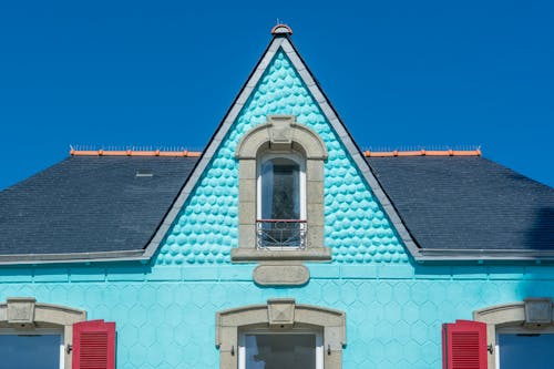 A blue house with red shutters and a blue roof