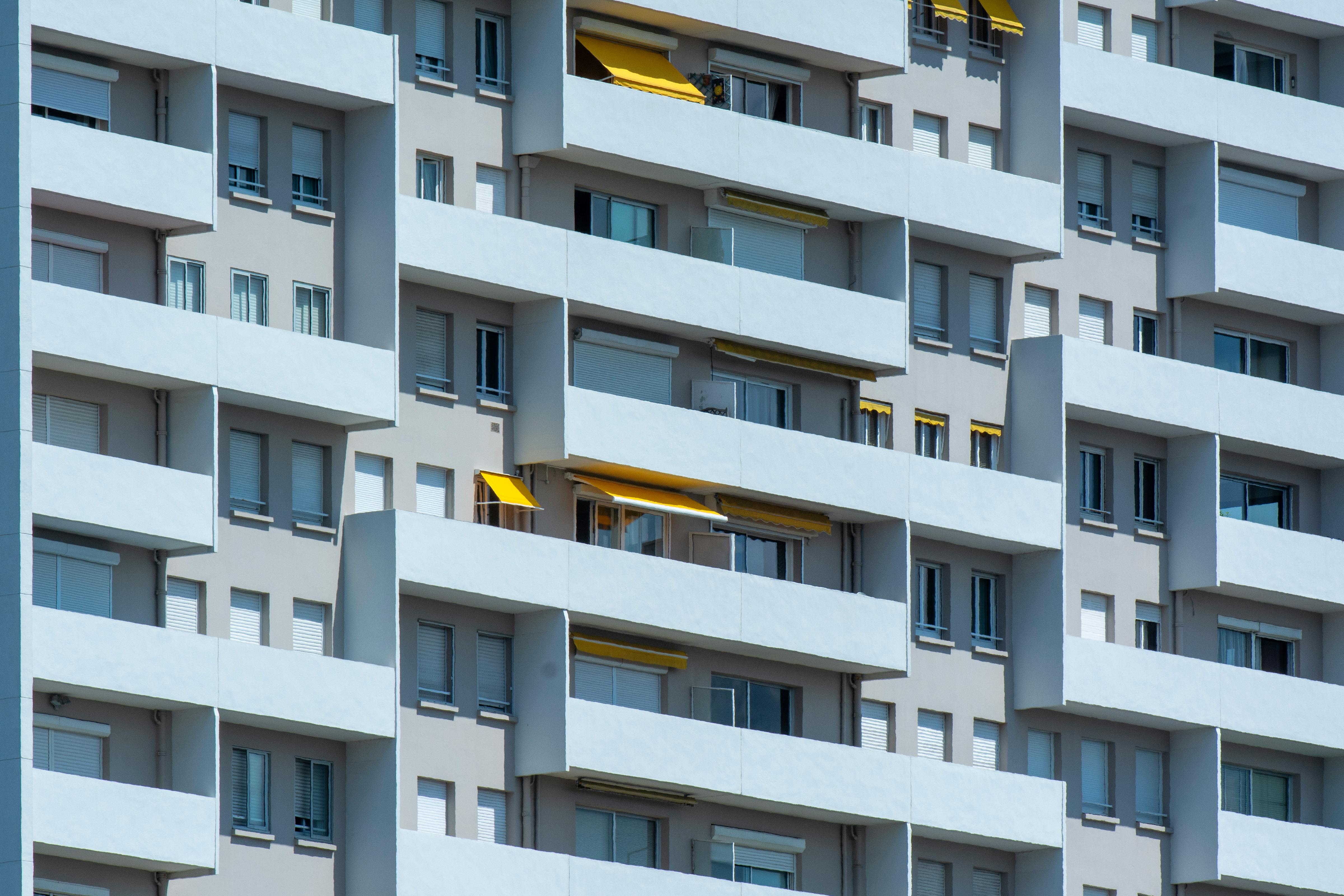 Close-up of a residential building facade with balconies and sunlight casting shadows.