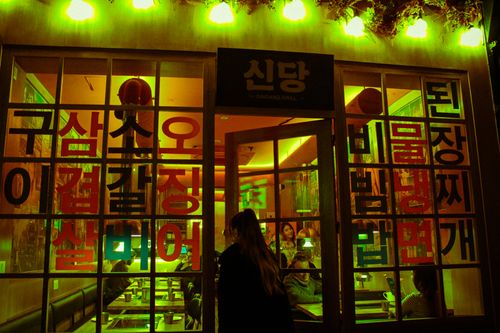 Free A woman entering a Korean restaurant at night. Vibrant lighting. Stock Photo