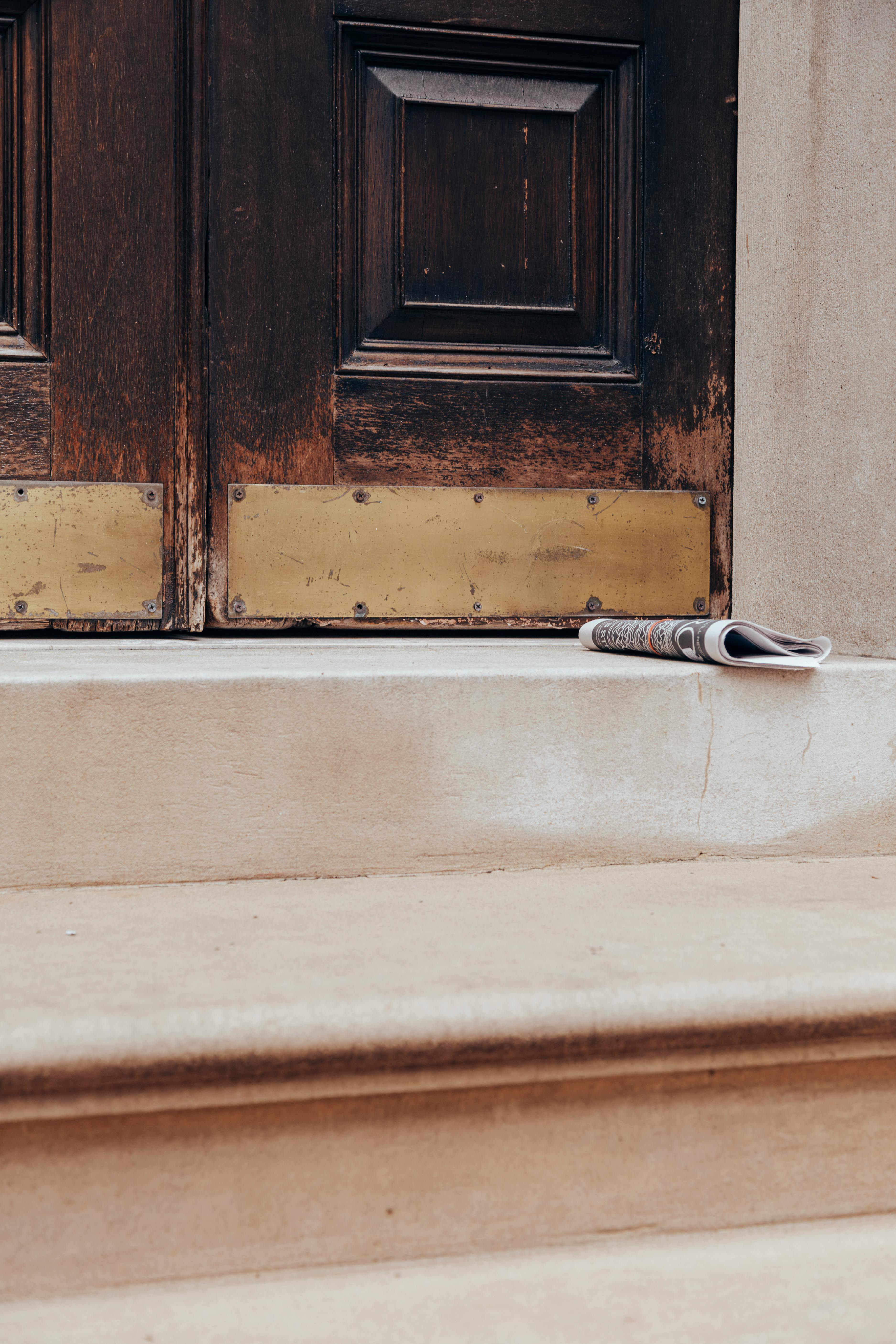 A vintage doorway with a newspaper on the steps, perfect for urban or architectural themes.
