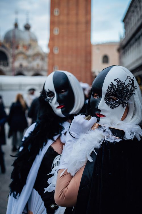 Free Elegant masked individuals in traditional Venetian carnival costumes outdoors. Stock Photo