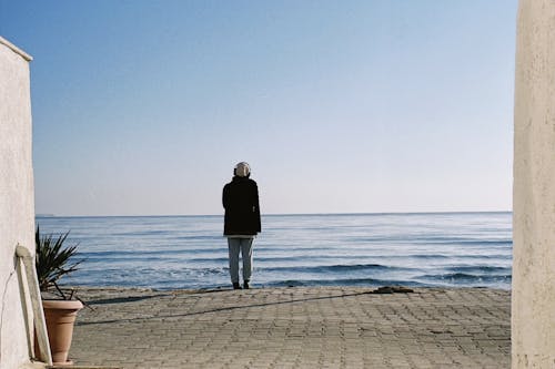 Person Standing on Street on Sea Shore