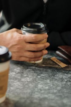 A close-up of hands holding a coffee cup on a marble table with copyspace.