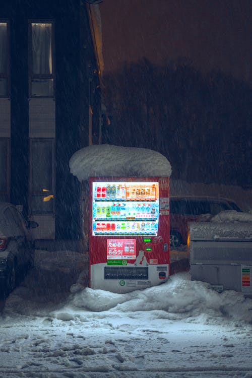 A vending machine in the snow at night